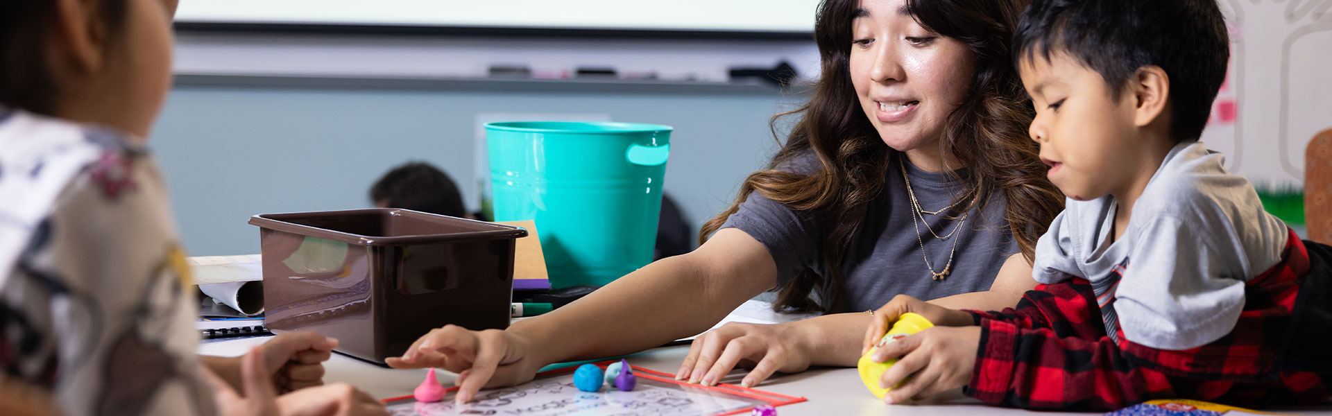 ksu teacher helping a young child with their work.