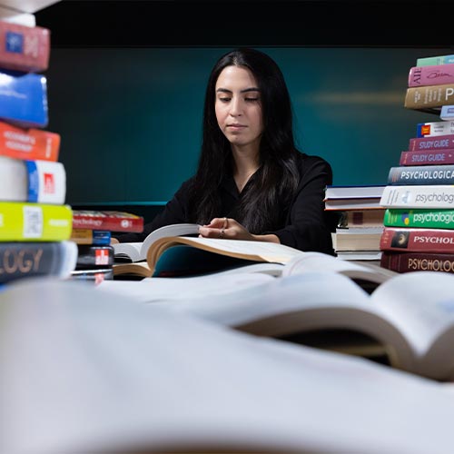 ksu transfer student surrounded by books.