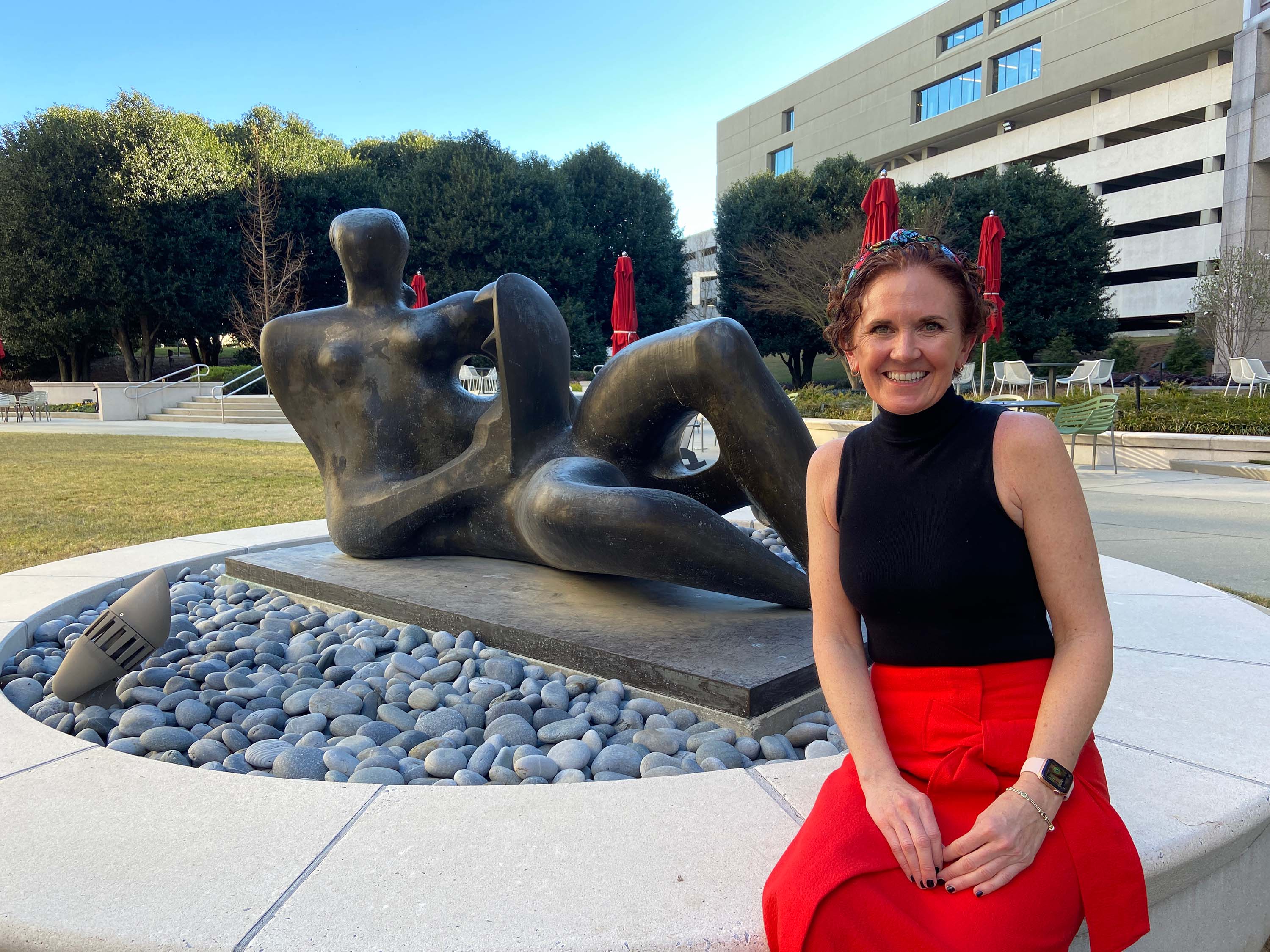 headshot of a woman sitting in front of a bronze statue