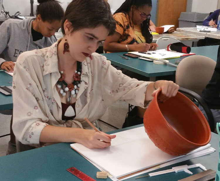 woman examining pottery artifact