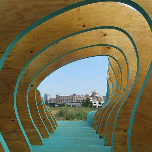 A beautifully designed archway where a building can be see at the opposite end. 