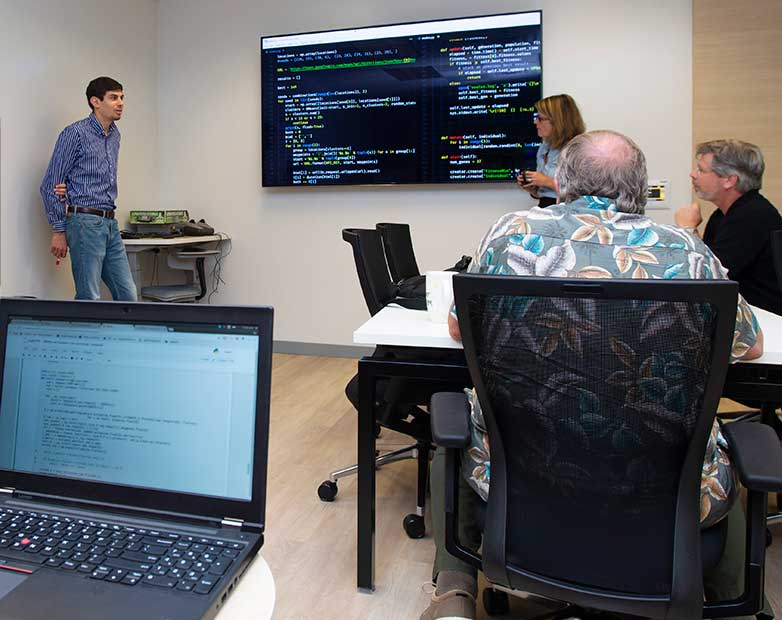 Data science graduate student mentoring undergraduate students reviewing a coding project