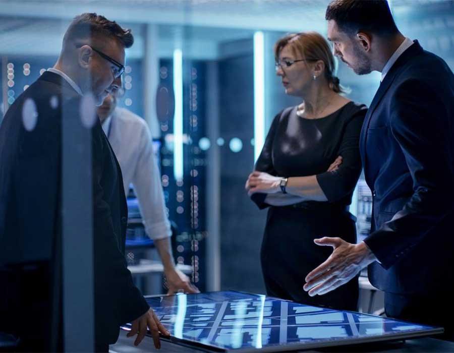 group of people surrounding a interactive table discussing information technology.