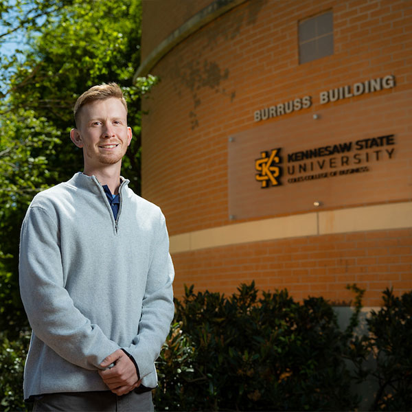 KSU Finance student standing infront of the Coles College Burruss Building.