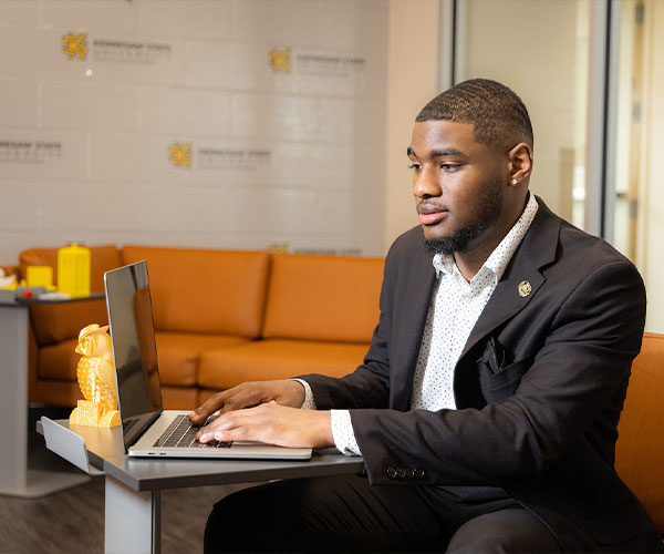 KSU student sitting at computer researching the Scholars Program