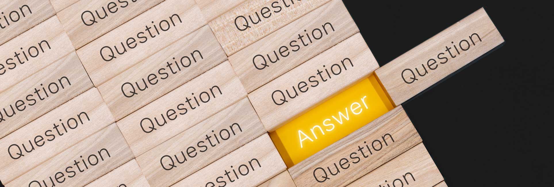 A collage of wooden blocks with the word "Question" engraved on each block, except for one block that has the word "Answer" engraved on it. The "Answer" block is positioned horizontally, breaking up a vertical pattern of the other blocks.