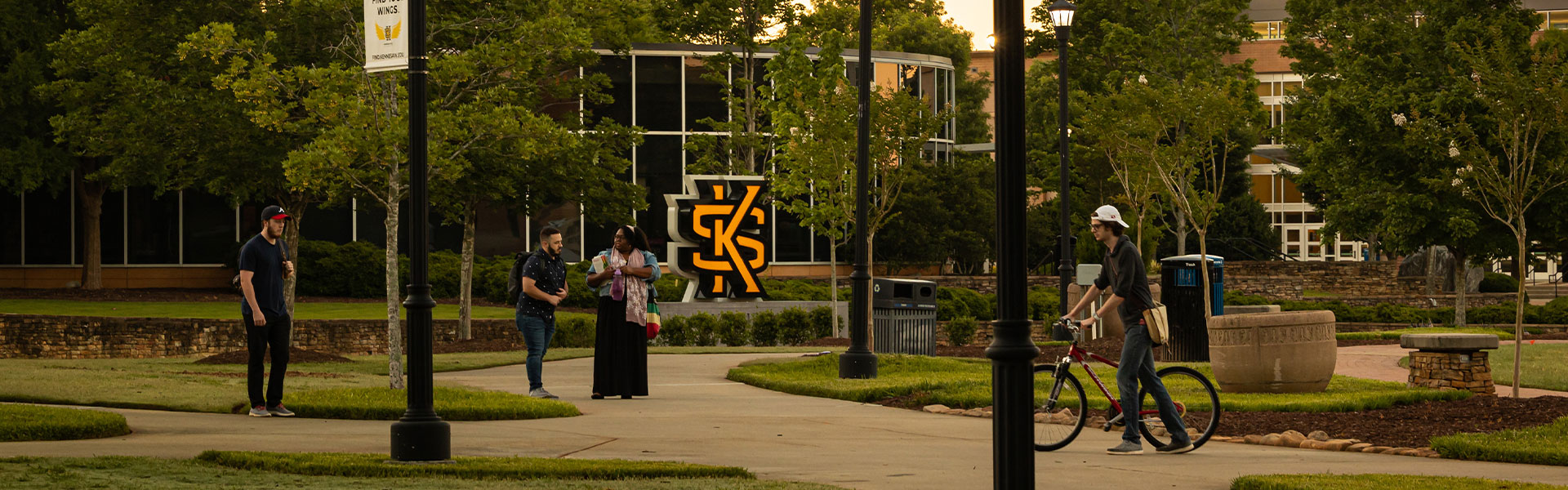 ksu students walking and biking on campus green