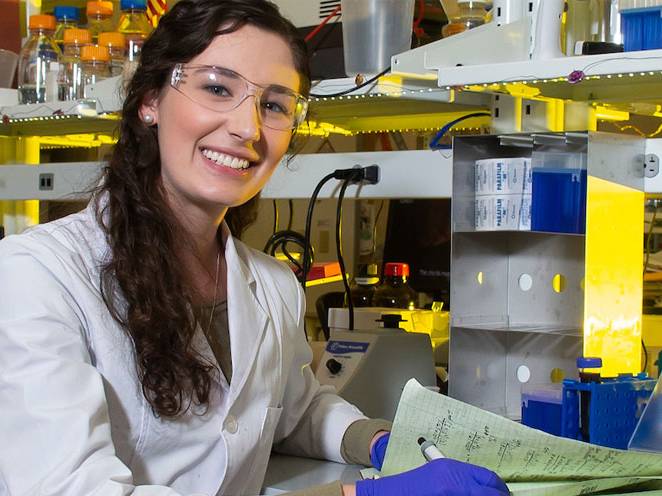 Woman wearing safety goggles and gloves taking notes 