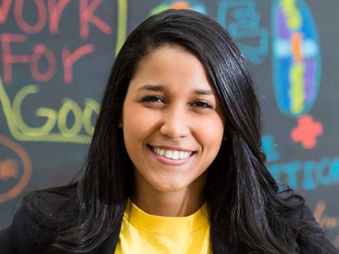 Business student smiling for a picture infront of a colorful chalk board