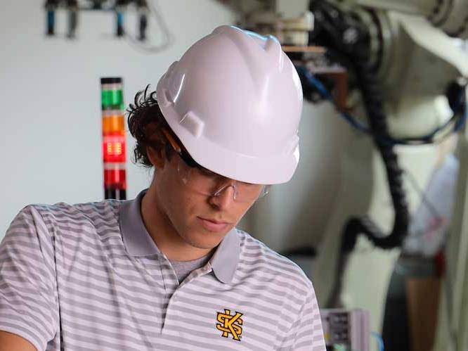 Student is wearing a hard hat with safety goggles working on a project