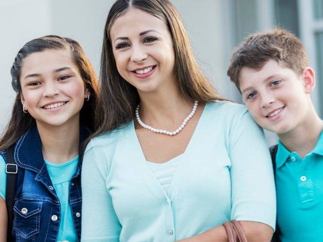 Woman and younger children standing together smiling for picture