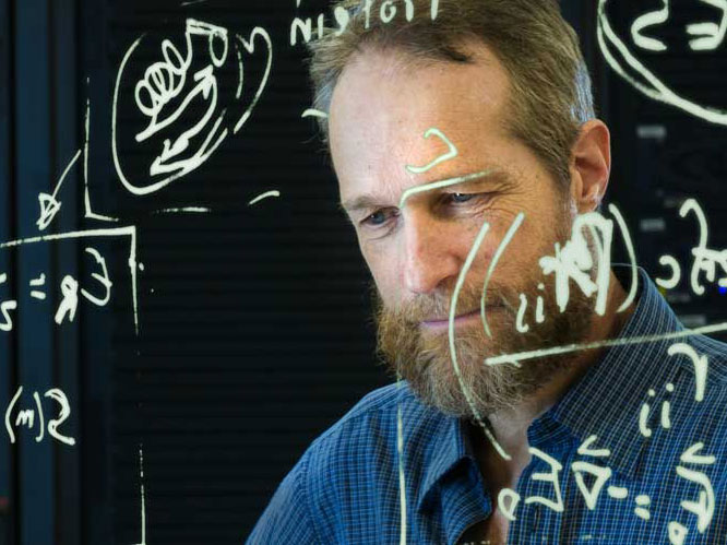 Man looking at a piece of glass with math equations on it