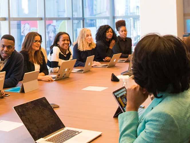 A group of men and women sitting at a large table communicating with eachother