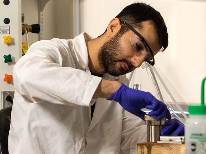 Man with saftey goggle and lab coat is doing a science experiment