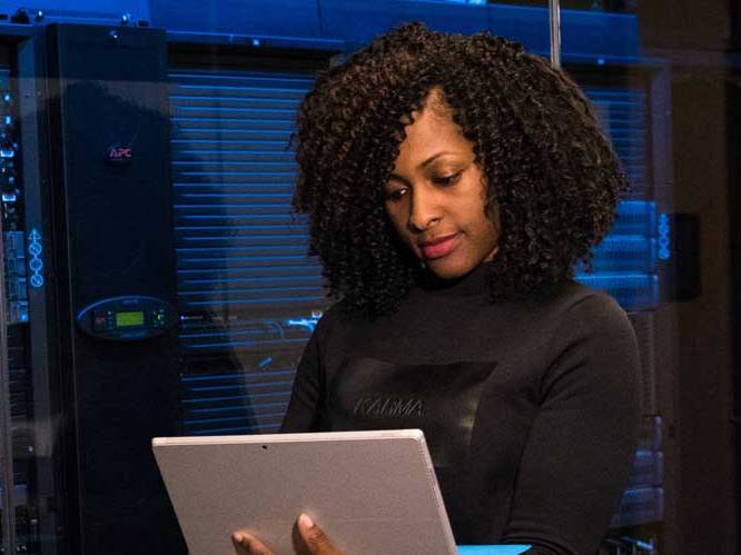 Woman standing up holding laptop focusing