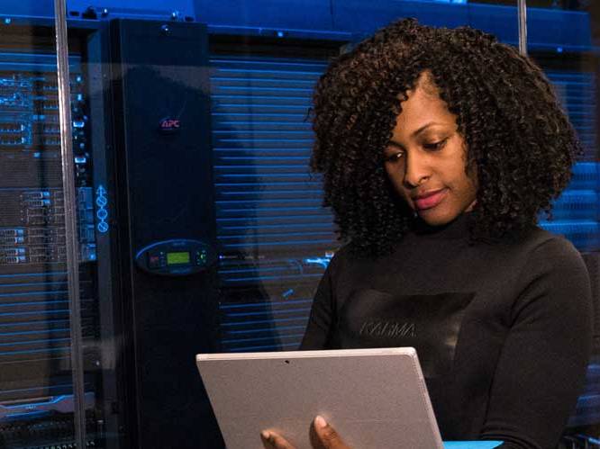 Woman standing holding a laptop focusing