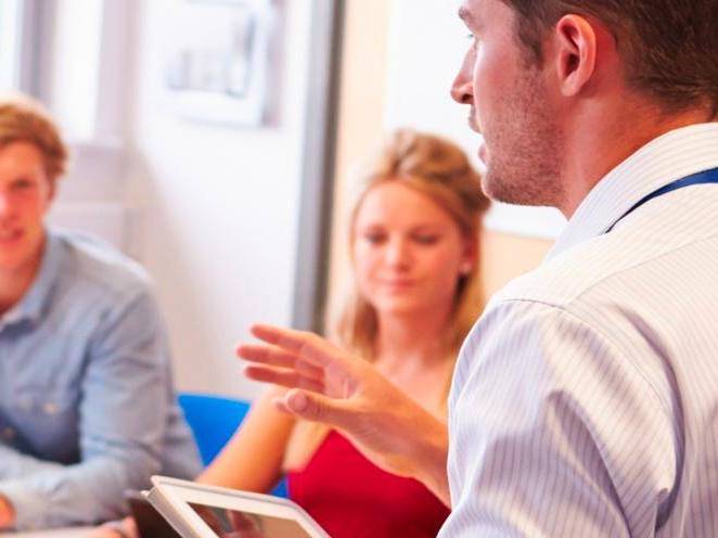 Man holding a tablet speaking toa man and woman