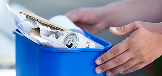 KSU Student holding a recycling bin with recyclables in it.