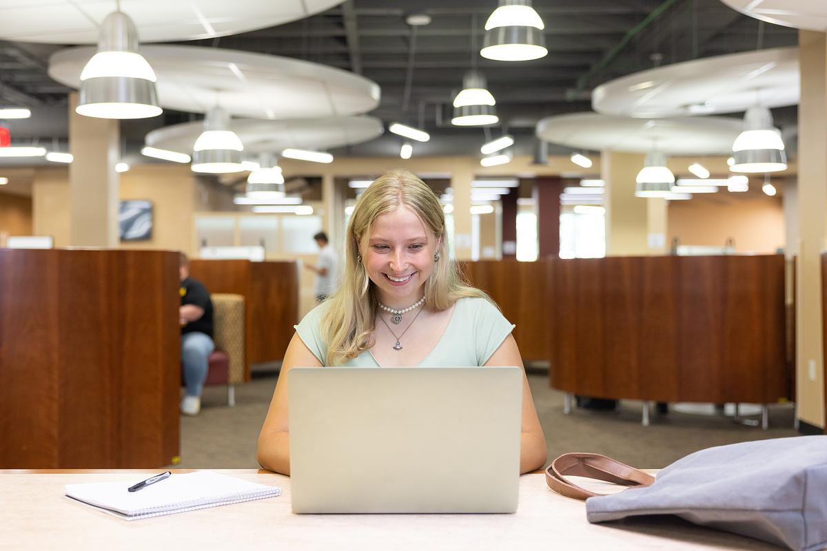 ksu student in the library using their laptop.