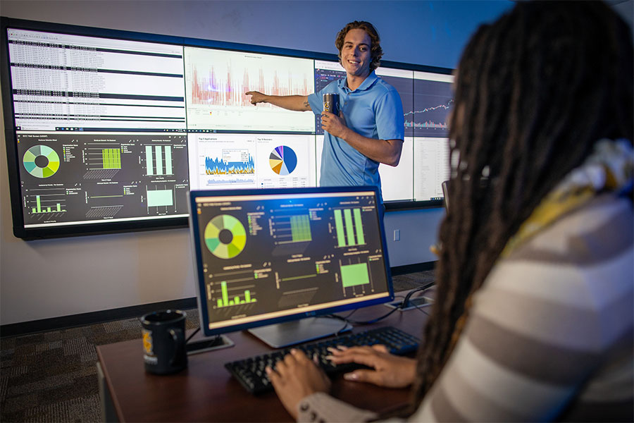 Photo of two people looking at data on large screens