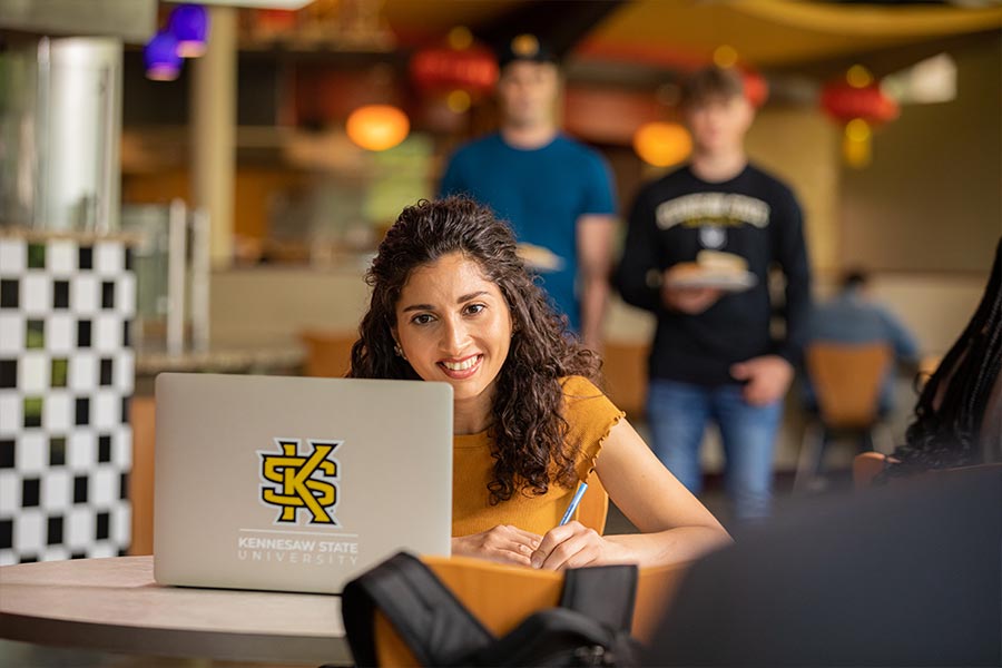 happy international student using their laptop at a table.