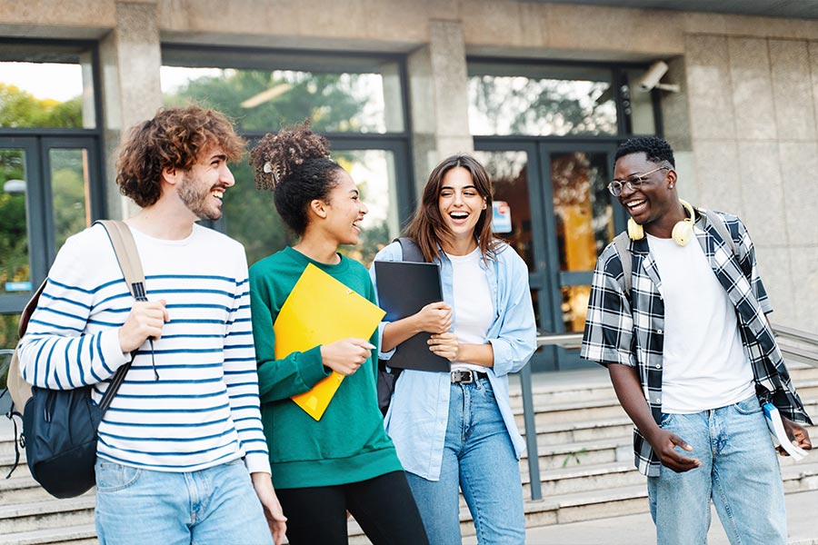 group of laughing international students walking out of a building on campus.