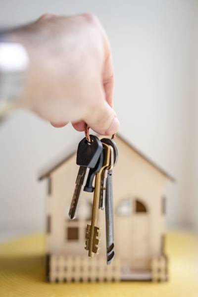 hands holding keys with a house in the background.