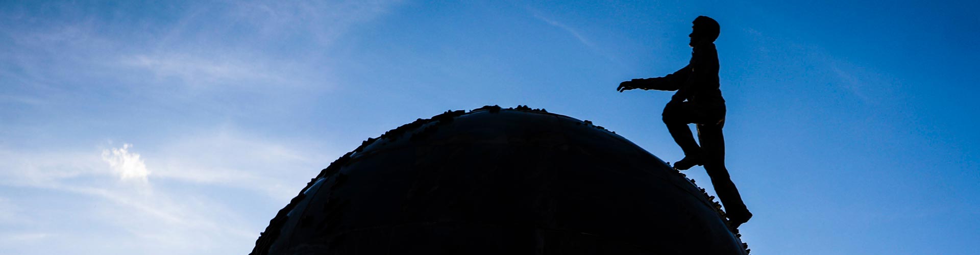 Closeup of the top of Spaceship Earth (sculpture) showing a man walking over a globe