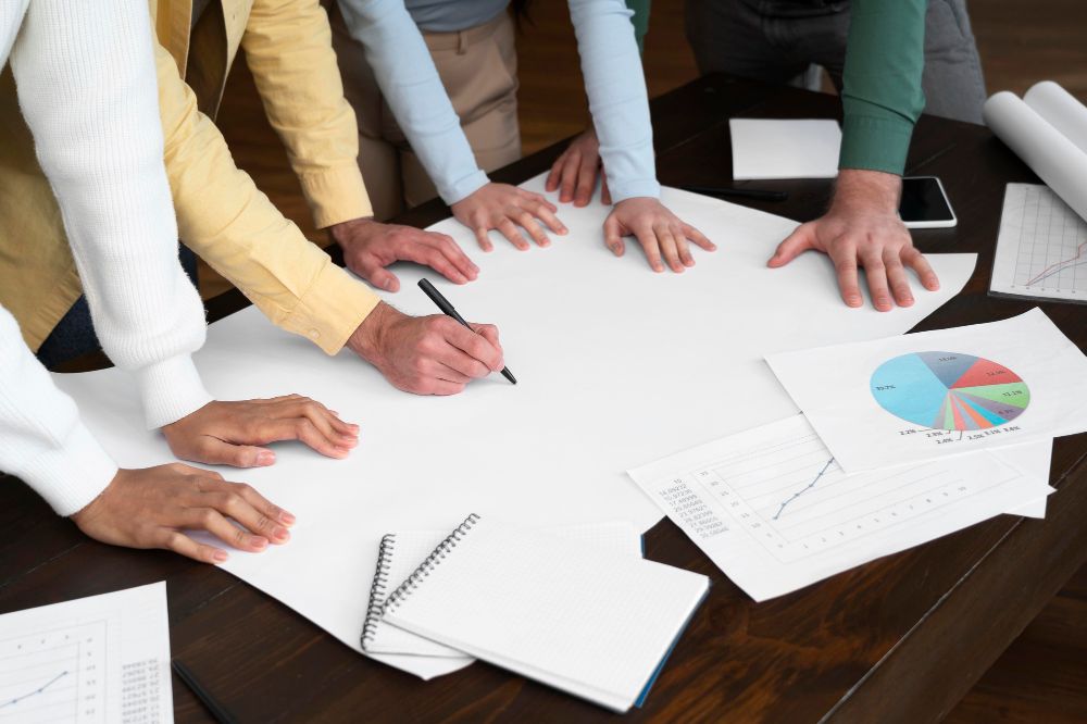 Faculty gathered around a desk discussing and writing a proposal