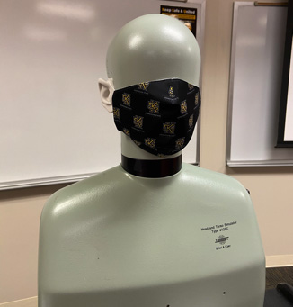 A mannequin head wearing a black face mask with KSU in a gold pattern.