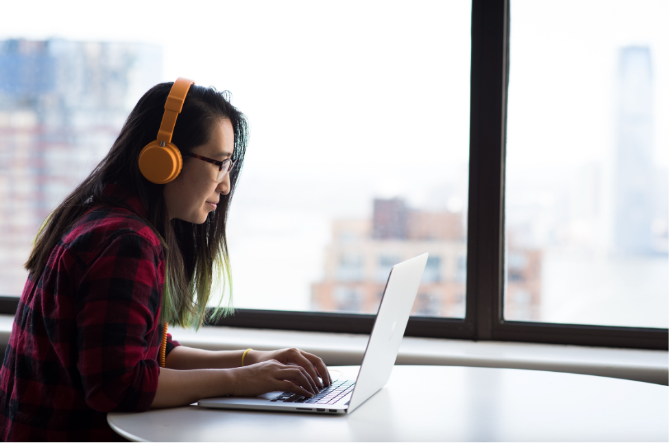 Student researching on a laptop with headphones