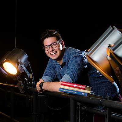 student leaning forward on a railing and smiling