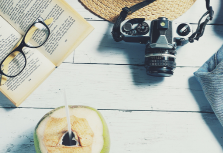 a table with a book, sunglasses, and a camera sitting on it.