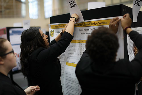 Student at a conference perparing their research on a printed poster