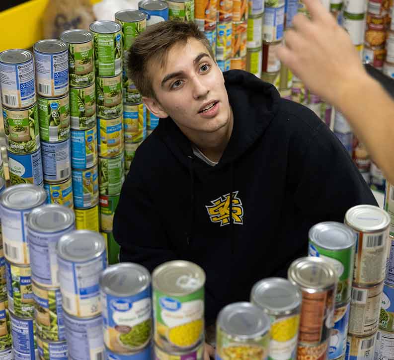 ksu student volunteering at food panrty sorting can goods