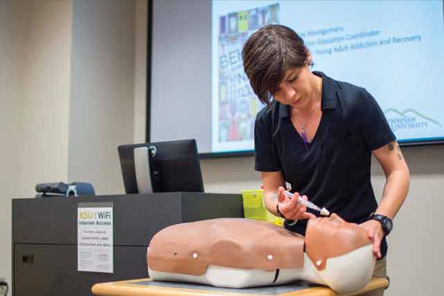 A person using a syringe to demonstrate on a dummy