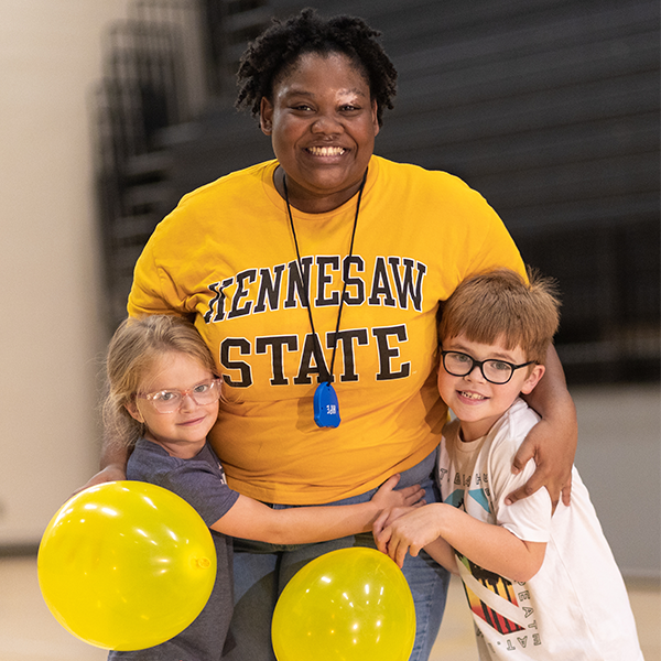 woman with 2 kids and 2 yellow balloons